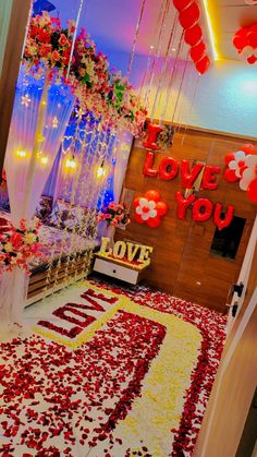 a room decorated in red and white with flowers on the floor, balloons hanging from the ceiling