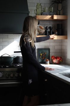 a woman standing in a kitchen preparing food on top of a counter next to an oven