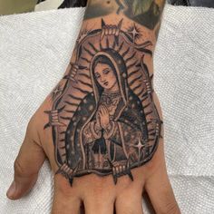 a person's hand with a tattoo on it and a virgin mary in the middle