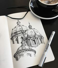 an open book with a pen and drawing on it next to a cup of coffee