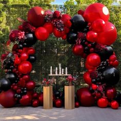 a large red and black balloon arch is set up for an outdoor ceremony with candles