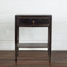 an old wooden table with a drawer on it's side, against a white brick wall