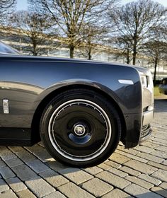 a black rolls royce parked on a brick road