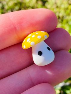 a tiny yellow mushroom sitting on top of a persons hand