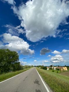 an empty road with some clouds in the sky