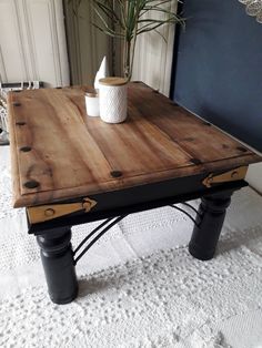 a wooden table with metal legs and a potted plant on top