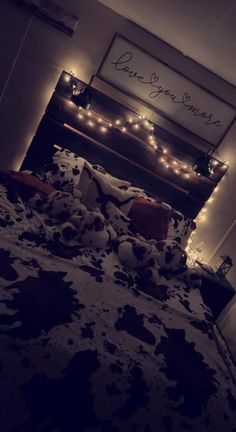 an unmade bed with lights on the headboard and comforter in front of it