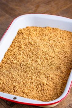 a red and white casserole dish filled with brown sugar on top of a wooden table