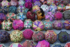 there are many different colored umbrellas for sale in this market place with caption that says, what would you pick?