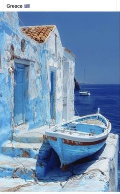 an old blue boat sitting on the side of a building next to the ocean with boats in the water