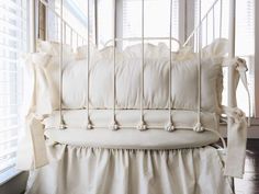 a white day bed with ruffles and pillows on it in front of a window