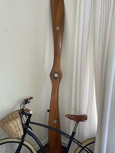 a bike parked next to a tall wooden clock on the side of a white wall