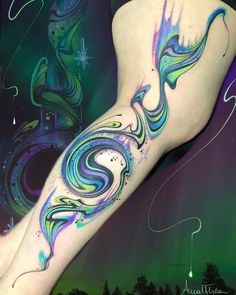 a woman's leg with colorful swirls on it and trees in the background