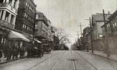 an old black and white photo of people walking down the street