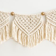 three crocheted wall hangings with wooden pegs attached to the top and bottom