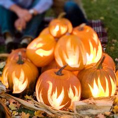 pumpkins with flames carved into them sitting on the ground in front of some people