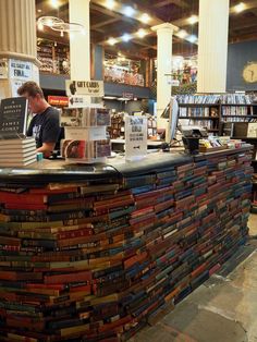 a man standing behind a counter covered in books