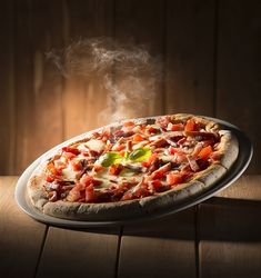 a pizza sitting on top of a pan covered in toppings and steam rising from it