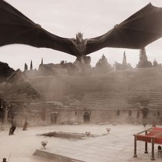 a large dragon flying over a stone building