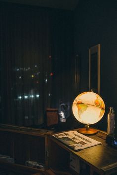 a desk with a lamp on top of it next to a book and cell phone