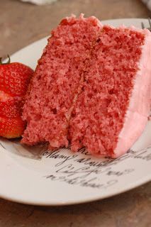 a piece of red cake on a plate next to a strawberry