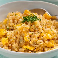 a white bowl filled with yellow rice and garnished with parsley on top