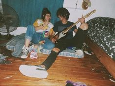 two people sitting on the floor playing guitars