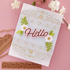 a card with the word hello written on it and some paper flowers next to it