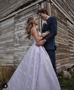 a man and woman standing next to each other in front of an old wooden building