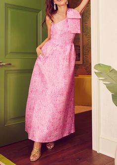 a woman standing in front of a green door wearing a pink dress