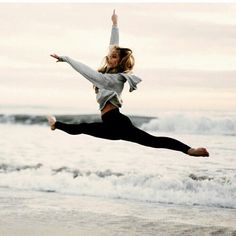 a woman is jumping in the air at the beach