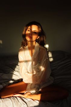 a woman sitting on top of a bed next to a window