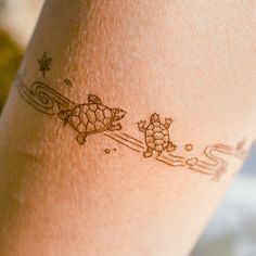 a tattoo on the leg of a woman with two small turtles riding skis and snowboards