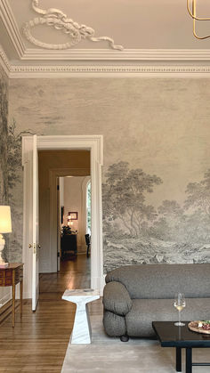 a living room filled with furniture and a painting on the wall above it's doorway