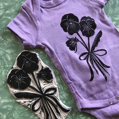 a purple bodysuit with black flowers on it next to a metal object that looks like a flower