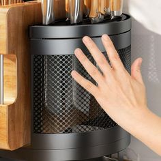 a person's hand reaching for knives in a holder