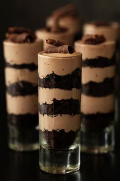 three glasses filled with desserts sitting on top of a table