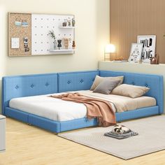 a bedroom with a blue couch and white rugs on the wooden floor, next to a bed