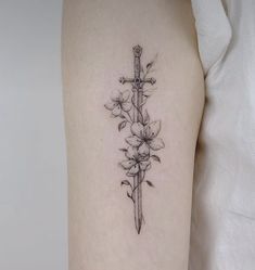 a cross and flowers tattoo on the right arm with a knife in it's center