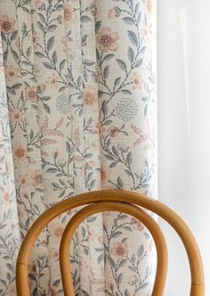 a wooden chair sitting in front of a curtain