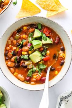 a white bowl filled with beans and avocado next to tortilla chips