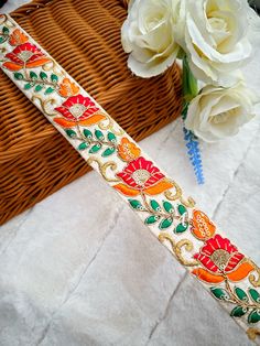 a close up of a ribbon on a table with flowers and a basket in the background