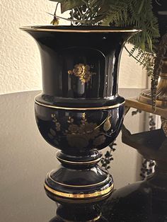 a black vase sitting on top of a table next to a planter with flowers in it