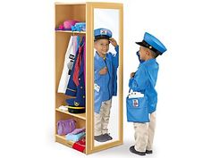 two children are standing in front of a mirror and looking at their own clothes on the shelf