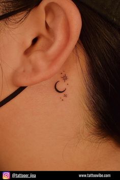 a woman's ear with a small crescent and stars tattoo on her left side