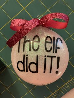 a glass ornament that says the elf did it with a red bow on top