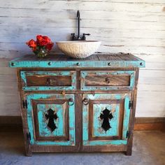 an old wooden cabinet with a bowl on top and flowers in the sink next to it