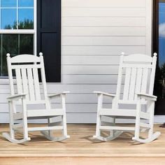 two white rocking chairs sitting next to each other on a wooden floor in front of a house