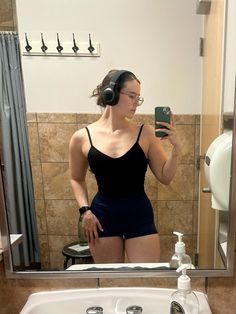 a woman taking a selfie in front of a bathroom mirror with headphones on