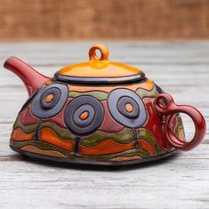 a colorful teapot sitting on top of a wooden table